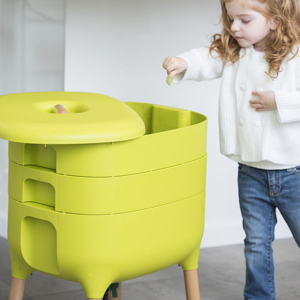 girl adding food scraps to green worm farm compost bin