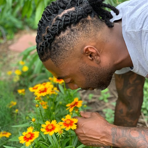 Timothy smelling a flower in his garden