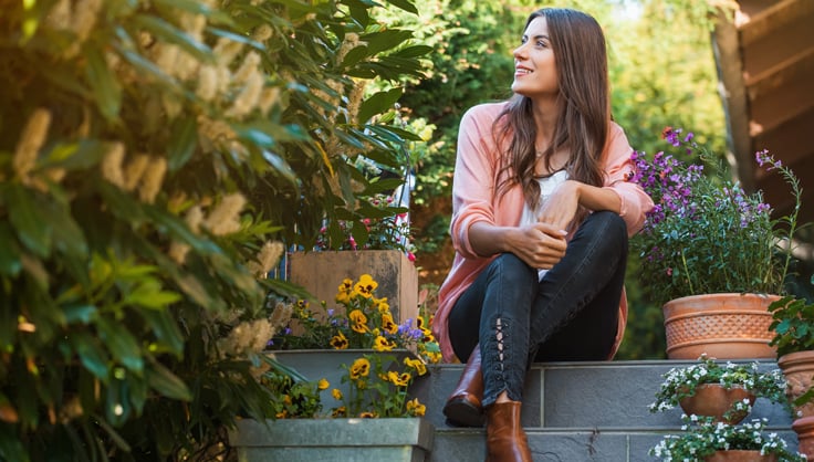 Woman sitting on steps among garden plants